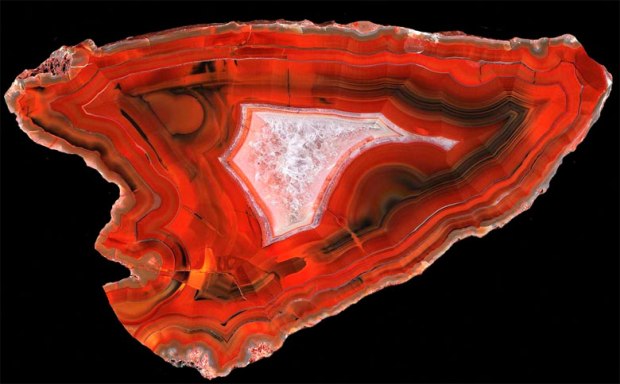 A large, bright red, banded agate in the shape of an arrowhead. 