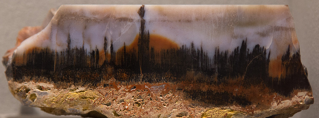 An agate that looks like a city skyline with an orange setting sun at the horizon.