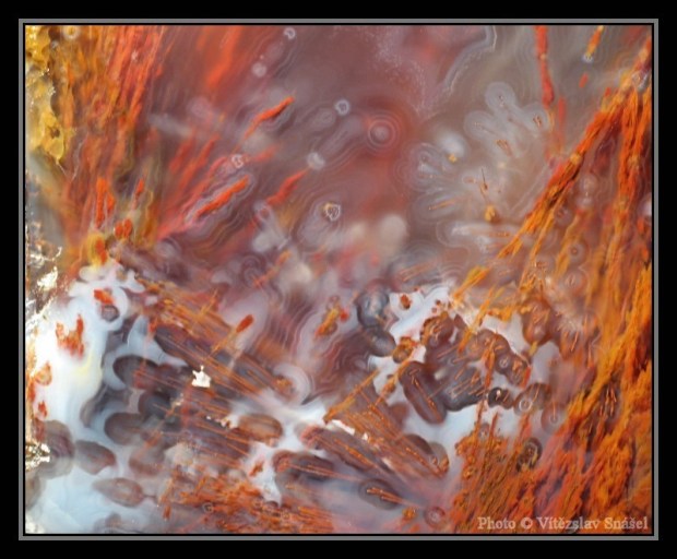 Red, orange, and yellow plumes shooting up from a white and transparent agate matrix, looking like flames. 