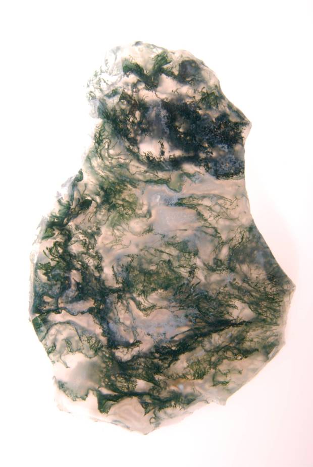A rounded white rock with green threads marbled over it, resembling seaweed.