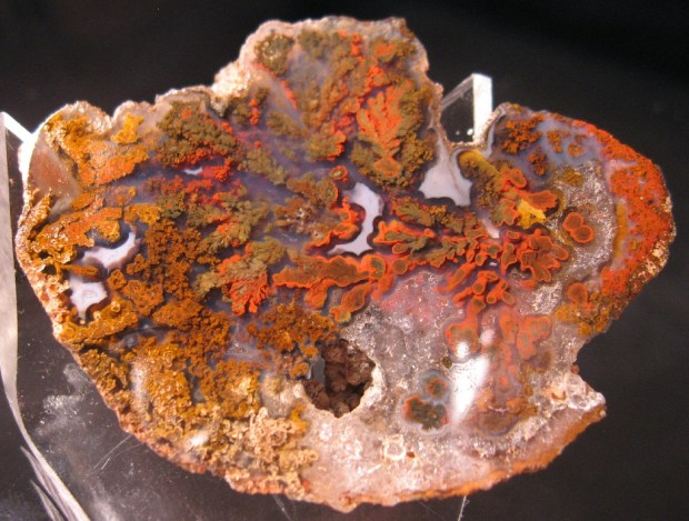 Light red translucent agate with red and orange puffy plumes appearing to float inside it.