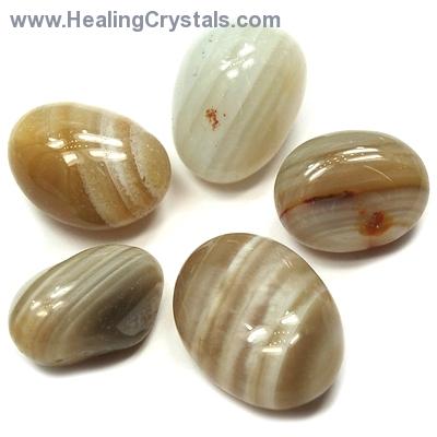 Five oval-shaped polished tumbled banded agate rocks with differing shades of brown and white stripes.