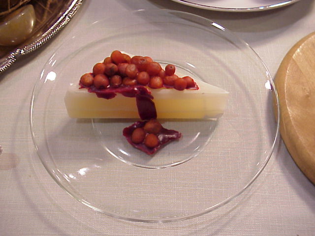 This looks like a slightly translucent slice of pale yellow cheesecake with small red cherries on top. It is actually a slice of rock with rocks on top.