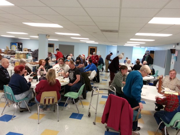 Adults and a few children eating dinner in a school cafeteria.