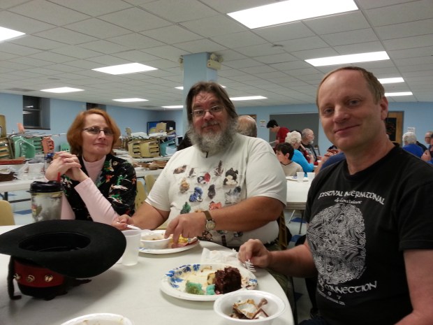 Three rockhounds smiling for the camera. One is wearing a shirt with rocks on it.