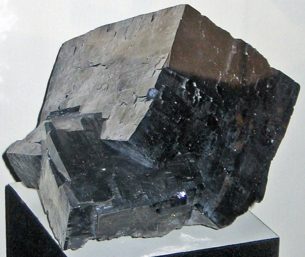 A huge shiny smooth silver-black cube on a display stand.