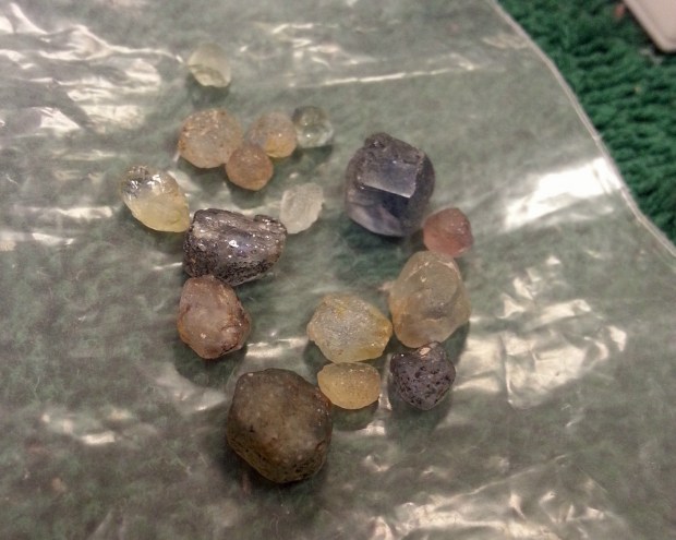 16 small irregularly shaped translucent stones ranging from colorless to blue.