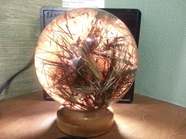 A glowing orange sphere with long dark spines (rutiles) trapped within. They look like tufts of fur.