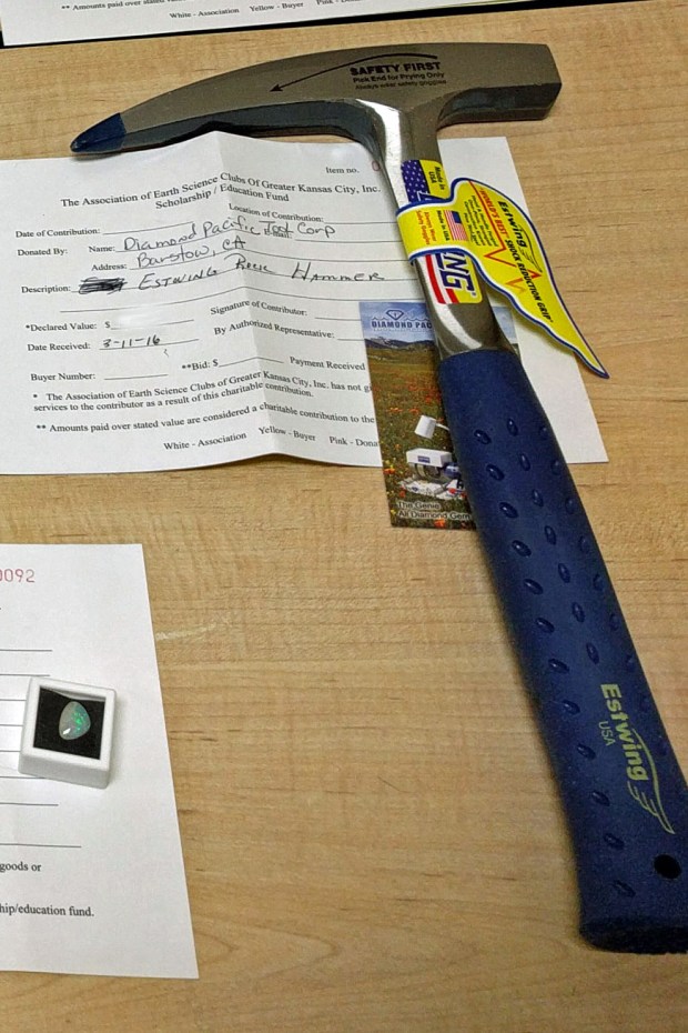 Estwing rock hammer next to polished opal