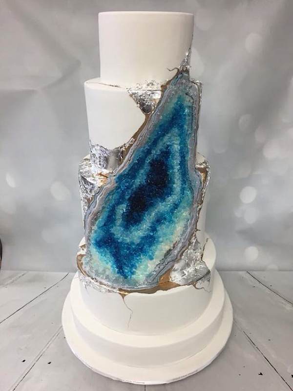 a white layered cake with a blue candy geode decoration