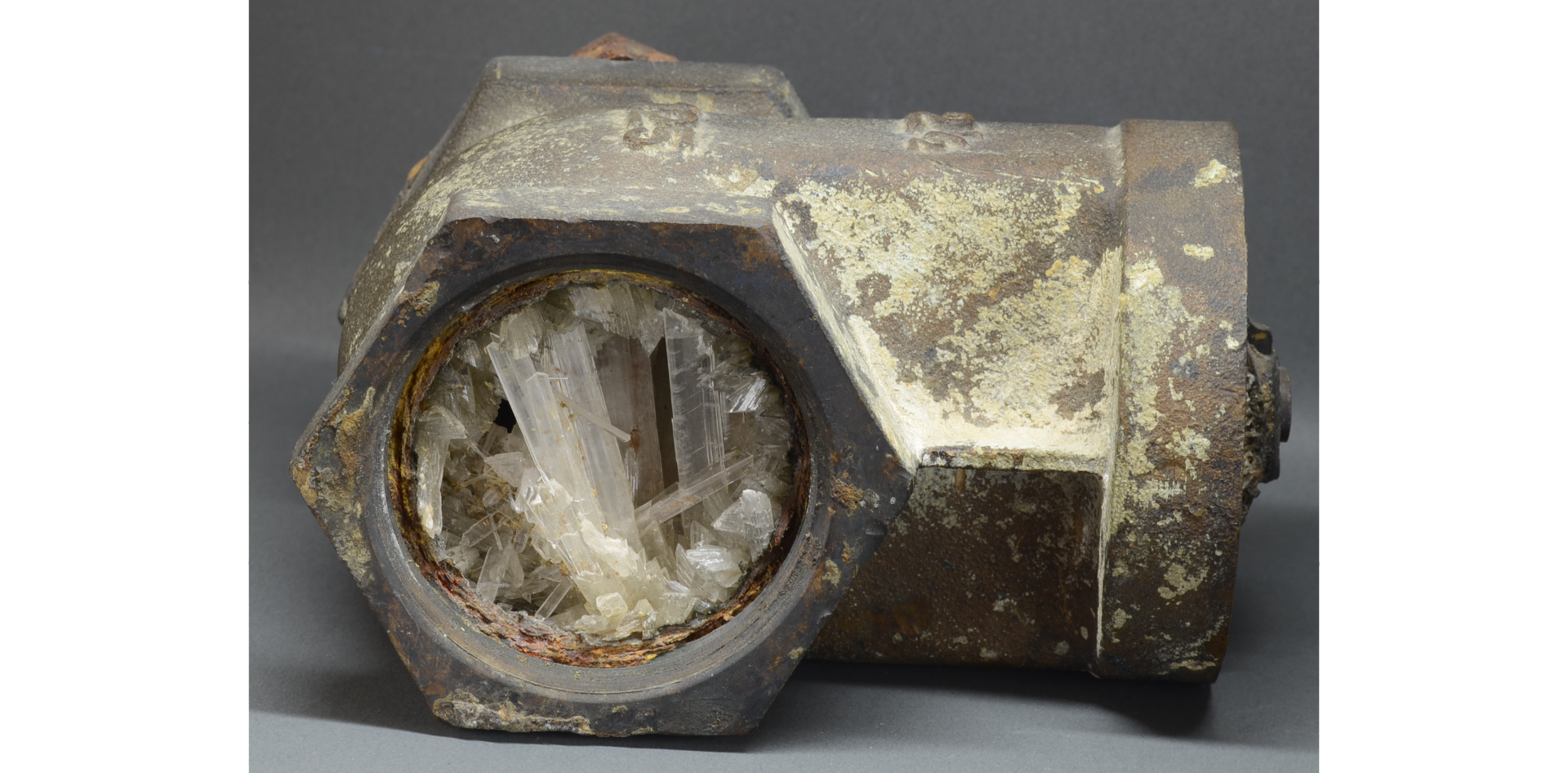 A metal pipe completely filled with white gypsum crystals